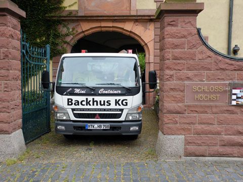Ein LKW der Backhus KG fährt rückwärts in die enge Einfahrt eines Schlosses.