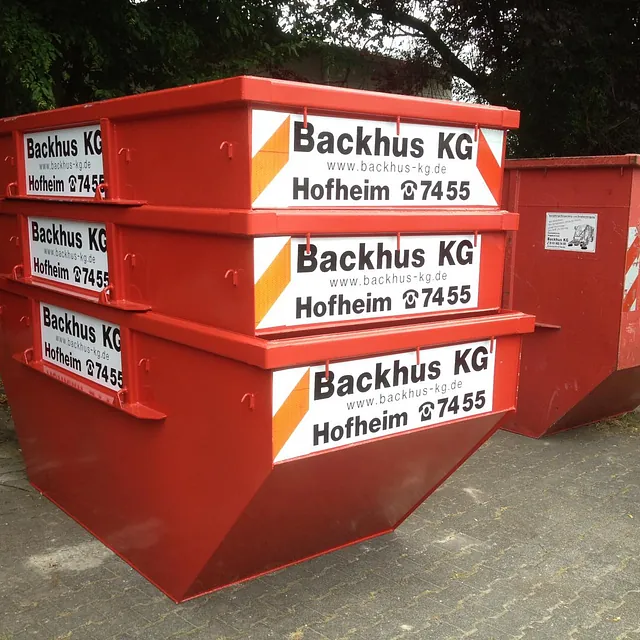 3 kleine gestapelte und 1 großer Container der Firma Backhus KG stehen bereit.
