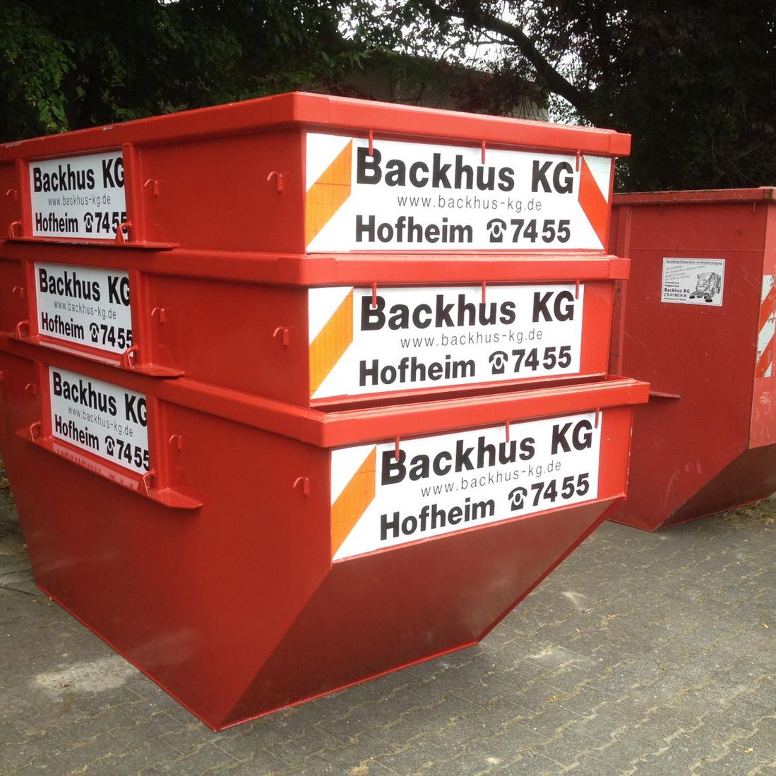 3 kleine gestapelte und 1 großer Container der Firma Backhus KG stehen bereit.
