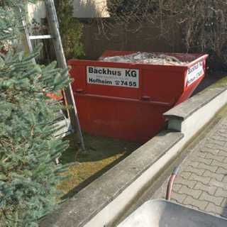 Der kleine rote Container von der Backhus KG passt auch in einen kleinen Garten.